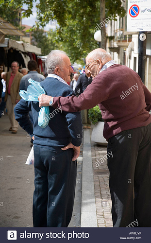 two-old-men-talking-on-street-at-the-annual-market-camucia-italy-AWRJYF